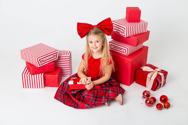 cute little girl sitting on studio floor with many gifts - Photo, Image