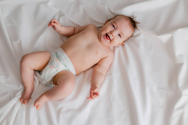 overhead view of cute baby lying on white sheets - Фото, зображення