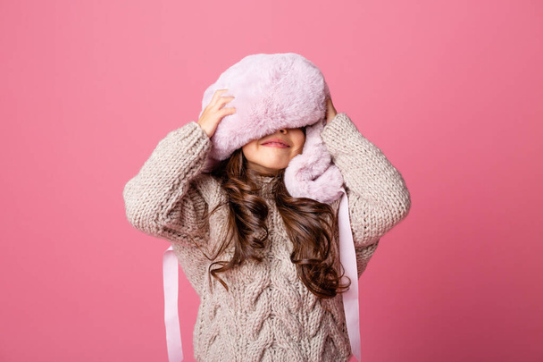 κοριτσάκι ποζάρουν σε χειμωνιάτικα ρούχα σε ροζ φόντο - Φωτογραφία, εικόνα