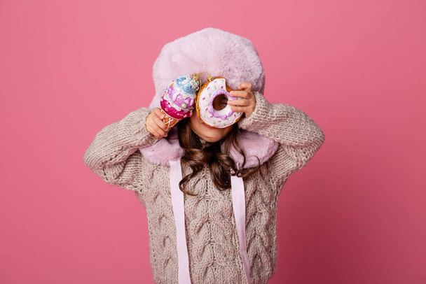 bambina in cappello caldo con palline di Natale in gelati e ciambelle - Foto, immagini