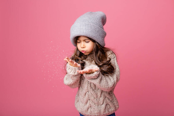κοριτσάκι με χειμωνιάτικα ρούχα που ποζάρει με ψεύτικο χιόνι  - Φωτογραφία, εικόνα