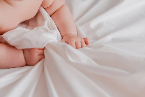 recortado tiro de pequeño bebé manos agarrando sábanas - Foto, imagen