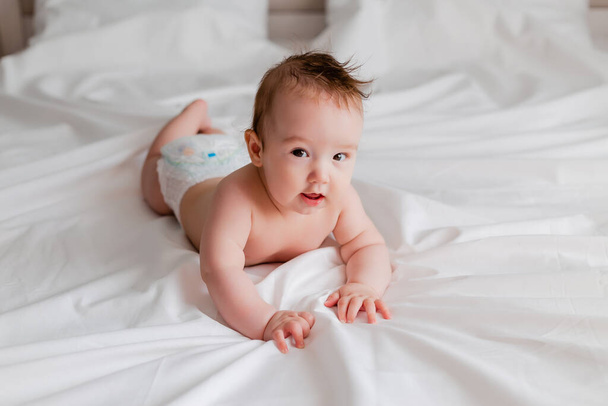 かわいい赤ちゃんがベッドの上の白いシーツの上に横になって - 写真・画像