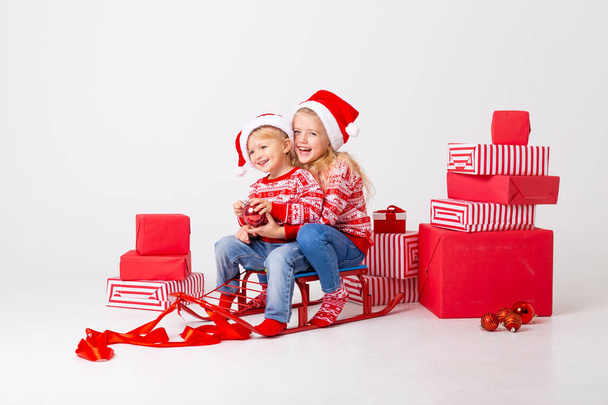 δύο παιδιά με χριστουγεννιάτικα καπέλα στο έλκηθρο με πολλά δώρα - Φωτογραφία, εικόνα