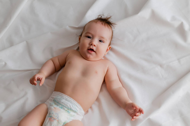 aranyos baba fekszik az ágyon fehér lepedő - Fotó, kép