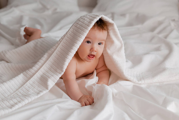 baby boy lying on bed with towel on head - Zdjęcie, obraz