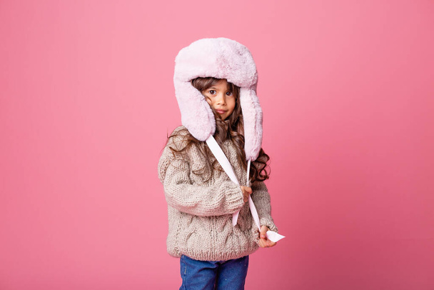 niña posando en ropa de invierno sobre fondo rosa - Foto, imagen