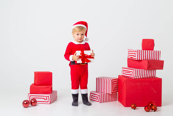 cute little girl in santa costume with many gifts in studio - Valokuva, kuva