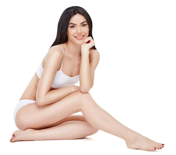 Fitness young woman with a beautiful body sitting on white background - Foto, afbeelding