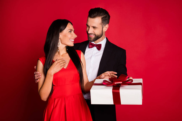 Photo of nice optimistic couple give present wear suit dress isolated on red color background - 写真・画像