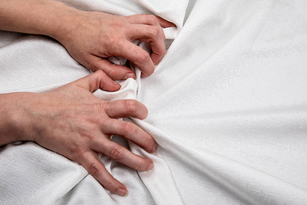 Two hands on a white cloth. Symbolizes stress, passion, love and sexual relationships - Foto, afbeelding