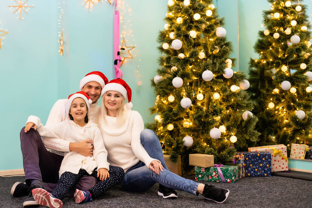feliz familia joven con un niño sosteniendo regalo de Navidad y sonriendo a la cámara - Foto, Imagen