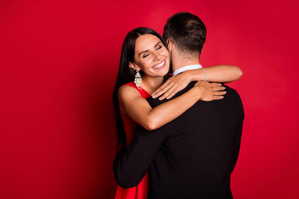 Photo of optimistic nice couple dance hug wear suit dress isolated on red color background - Foto, afbeelding