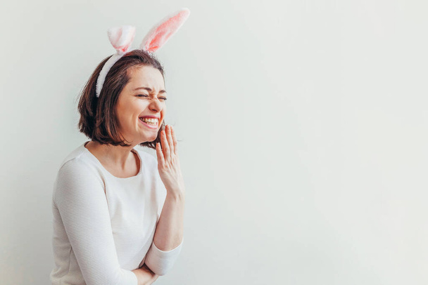 ハッピーイースターのお祝い春のコンセプト。白い背景にウサギの耳を身に着けている若い女性。休日の準備。女の子は幸せそして興奮しているイースターの日に楽しんで - 写真・画像
