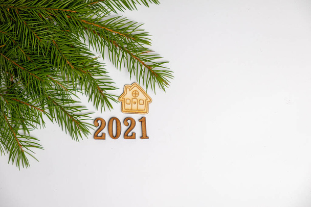 Різдвяний або новорічний фон з гілками зелених ялинок. Маленький будинок і номери 2021 року. Залишайтеся вдома концепцією і порожнім місцем для тексту
. - Фото, зображення