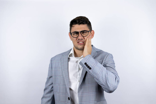 Business young man wearing a casual shirt over white background touching mouth with hand with painful expression because of toothache or dental illness on teeth - Photo, Image
