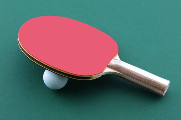 Rakietka do tenisa stołowego i biała piłka na zielonym stole do ping ponga - Zdjęcie, obraz