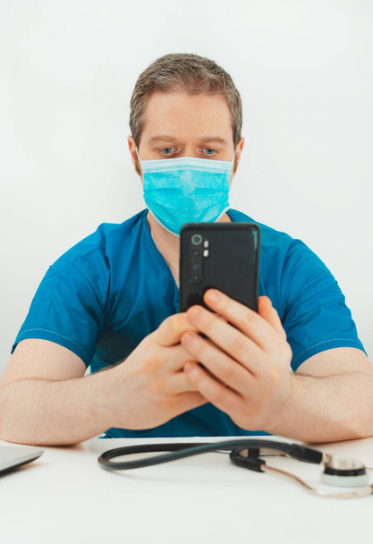 Médico en máscara protectora que tiene videoconferencia con el paciente. - Foto, Imagen