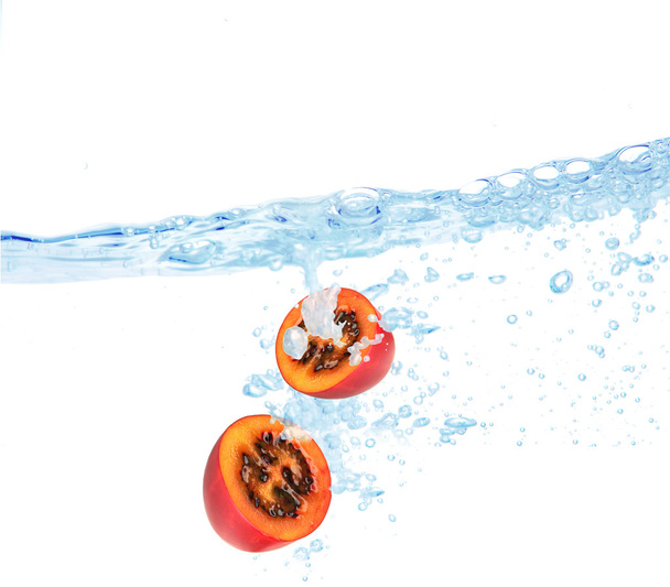 Juicy fruit dropped into water - 写真・画像