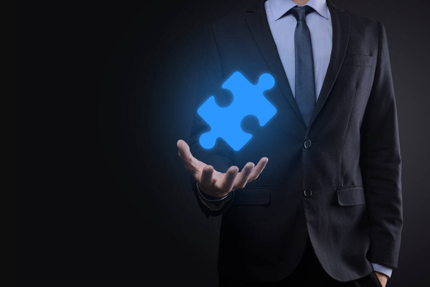Businessman holds a piece of puzzle jigsaw in his hands.The concept of cooperation, teamwork, help and support in business - Photo, Image