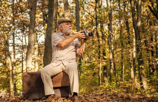 Cameraman outdoors. Professional photographer. Pension hobby. Retro photographer. Used to manual settings. Old man shoot in nature. Landscape and nature photo shooting. Old photographer filming - Photo, Image