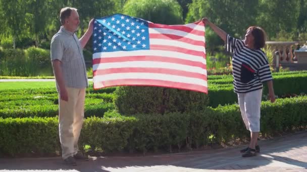 Joyful senior couple holding American flag. - Imágenes, Vídeo