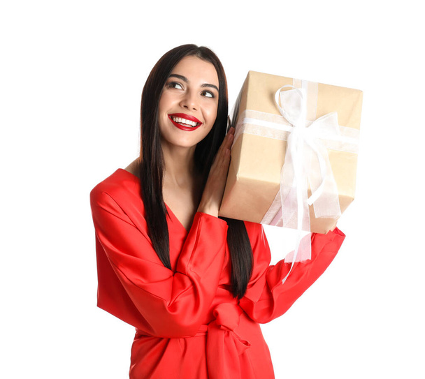 Woman in red dress holding Christmas gift on white background - 写真・画像