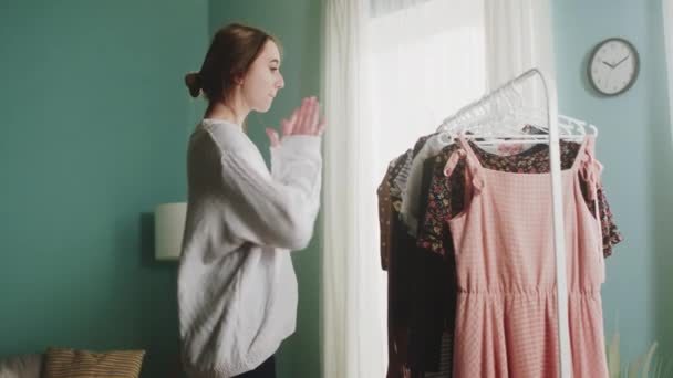 Nuori nainen iloisia tunteita valitsee vaatteita - Materiaali, video