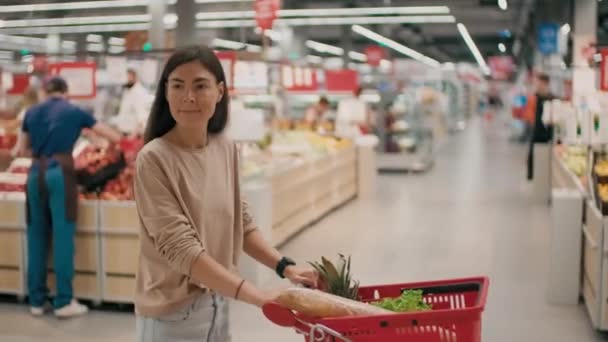 Medium shot of people doing daily shopping in big modern supermarket walking through aisles looking at counters - Video