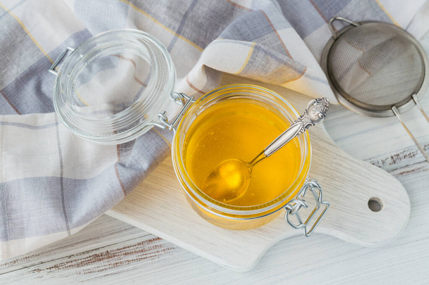 Healthy homemade Ghee or clarified butter in jar on white wooden table. Healthy Ayurveda food concept. - Fotó, kép