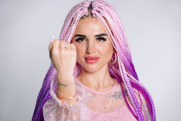 Portrait of a young blogger with pink hair showing her fist to the camera. White background. High quality photo - Foto, Imagem