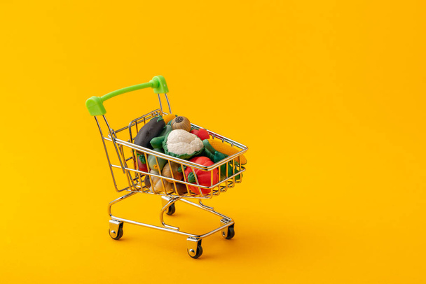 toy vegetables in a cart for food on a yellow background - Foto, Bild