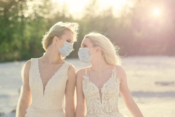 Lesbičky pár svatba na bílém písku, nosit masky, aby se zabránilo epidemii COVID-19 - Fotografie, Obrázek