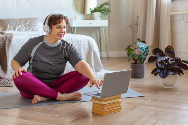 Vezető nő a fejhallgató készül otthoni edzés irányítása alatt egy online oktató. - Fotó, kép