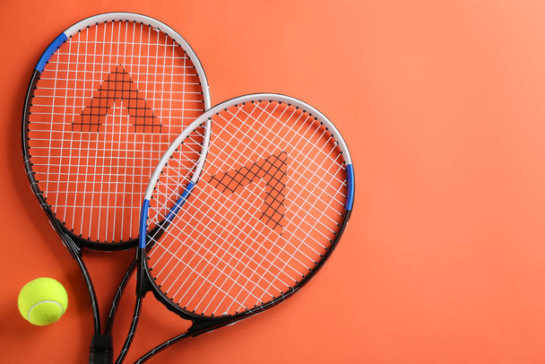 Tennis rackets and ball on orange background, flat lay. Space for text - Фото, изображение