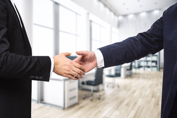 Handshake of two businessmen on the background of sunny modern furnished office, signing of a contract concept, close up - Foto, Imagen