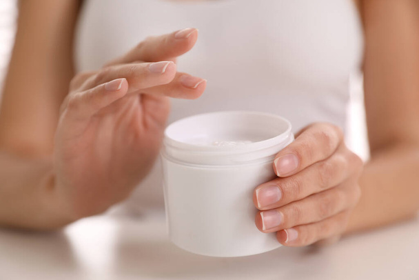 Woman with jar of moisturizing cream, closeup - Foto, immagini