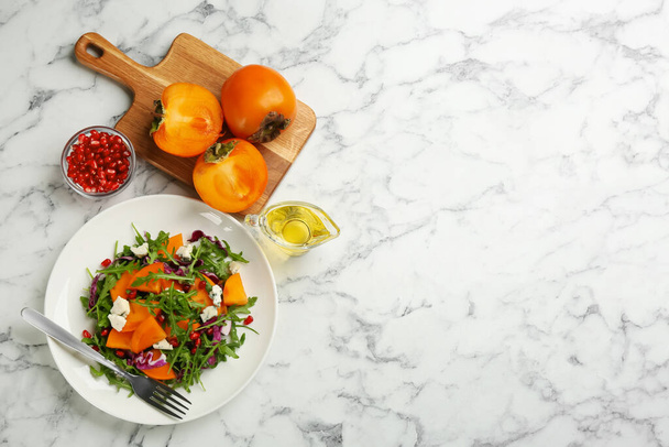 Delicious persimmon salad served on white marble table, flat lay. Space for text - Foto, immagini