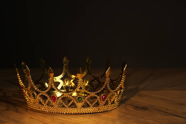 Beautiful golden crown with gems on wooden table. Fantasy item - Φωτογραφία, εικόνα