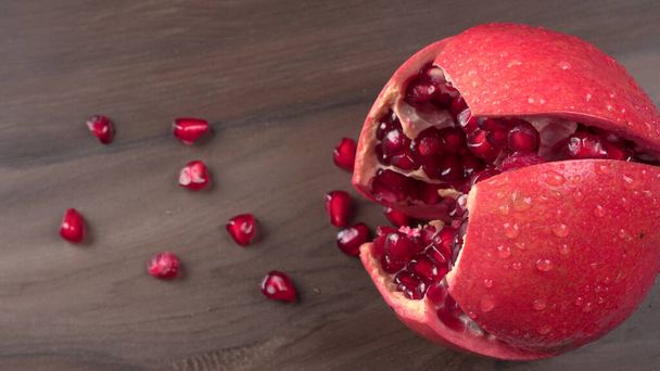 View of ripe pomegranates and pomegranate seeds on the table - Photo, Image