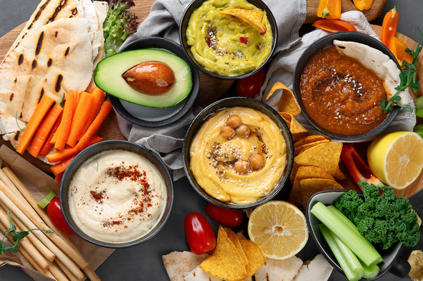 Different kinds of hummus dips with snacks. Traditional homemade snacks concept. Top view - 写真・画像