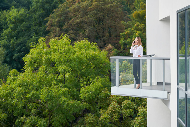 Businesswoman standing on balcony against nature - Φωτογραφία, εικόνα