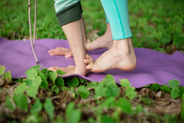 A young sports girl practices yoga in a quit green summer forest, yoga assans posture. Meditation and unity with nature. - Foto, Bild