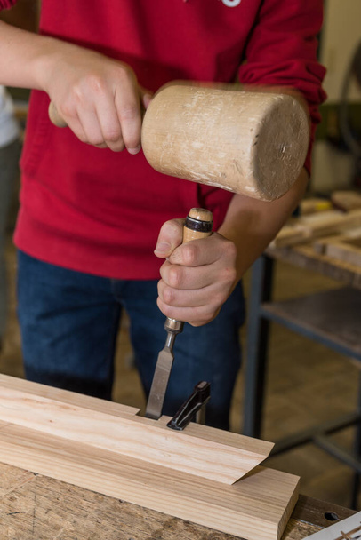 Carpenter works in workshop with wooden hammer and chisel - craftsman, carpenter - Photo, Image