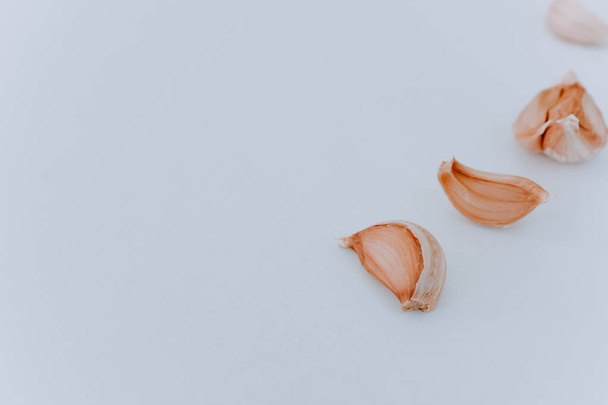Eine Handvoll rohe Knoblauchzehen auf hellem Hintergrund. Knoblauchzehen in Großaufnahme auf hellem Hintergrund. Seitenansicht. Zutaten zum Kochen. Gewürze zum Kochen - Foto, Bild