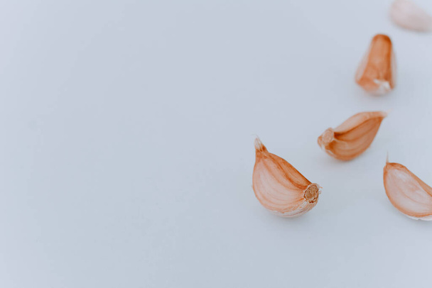 Un puñado de dientes de ajo crudos sobre un fondo claro. dientes de ajo de cerca sobre un fondo claro. Vista lateral. Ingredientes para cocinar. Especias para cocinar - Foto, Imagen