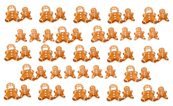 Pattern of gingerbread man in protective mask on white background. Christmas mood or food design. Creative copy space. Close-up - Photo, Image