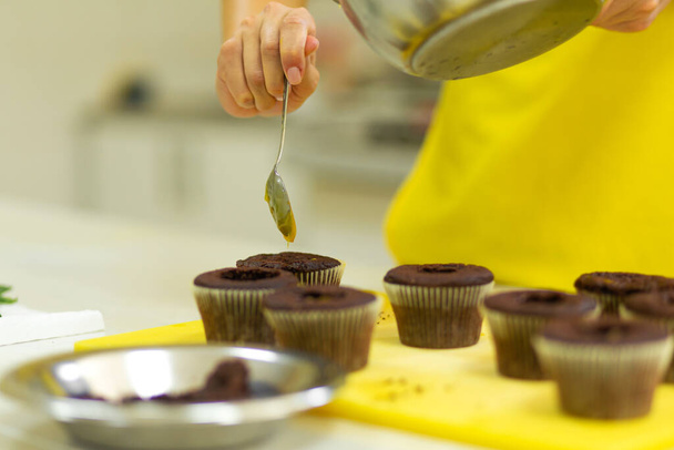 El proceso de hacer cupcakes de chocolate con crema dulce. Creación de pasteles por chefs profesionales de pastelería. - Foto, imagen