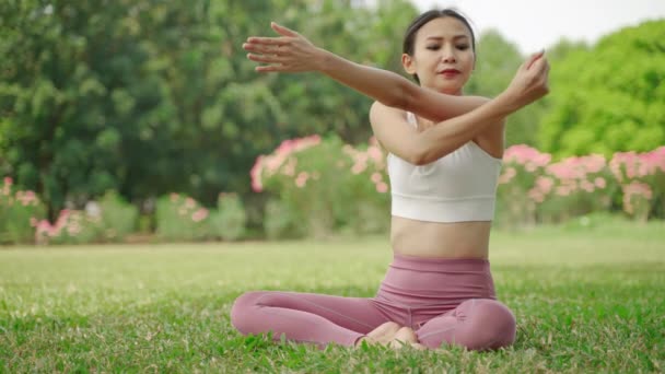 молодая азиатка сидела в йоге в саду, она была расслаблена и наслаждалась тренировкой. - Кадры, видео
