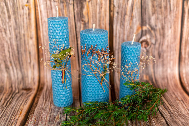 Blue honey candles handmade from natural wax on a background of wooden boards. Elements from natural materials. Christmas or New Years composition. Photo for postcards. - 写真・画像